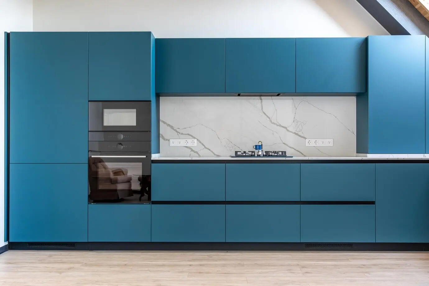 Cocina con estufa de gas, pared de mármol y muebles de cocina en acabado azul mate.